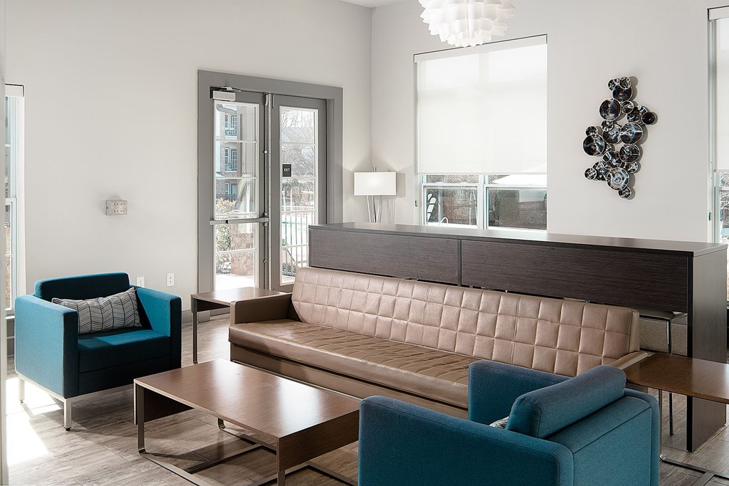 A modern room with a brown tufted couch and blue chairs.