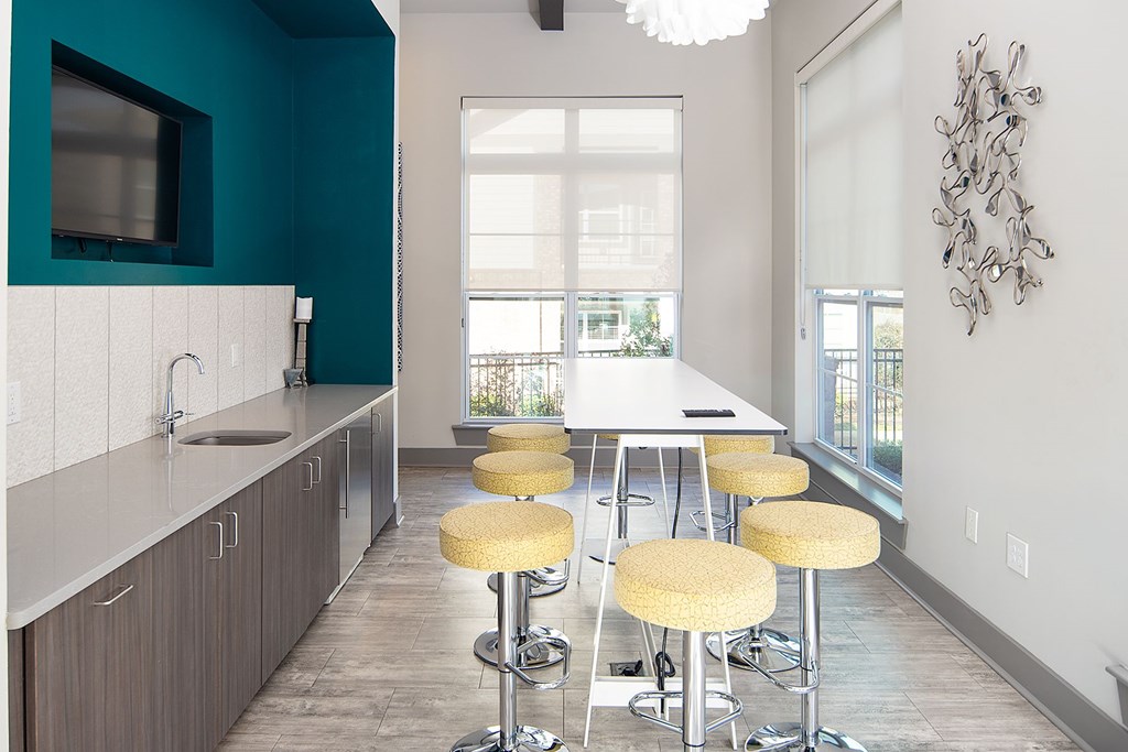 A room with a white table and yellow stools.