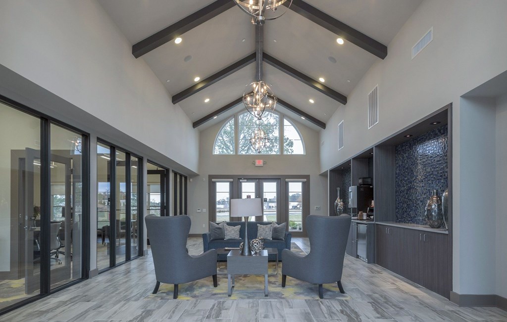 A large room with a chandelier and grey chairs.