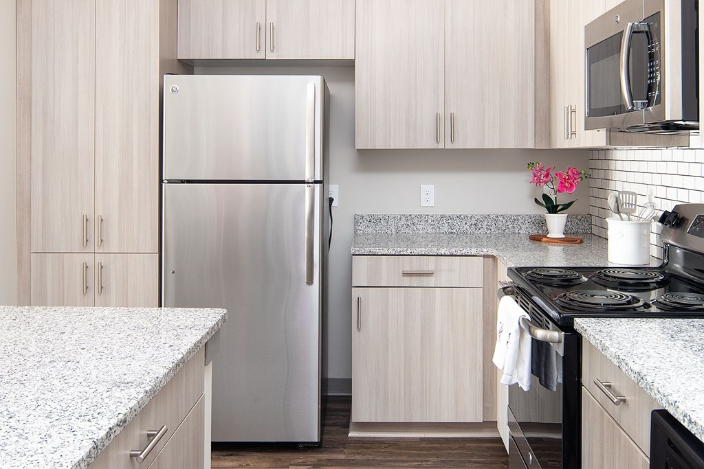 A kitchen with a refrigerator, microwave, and oven.