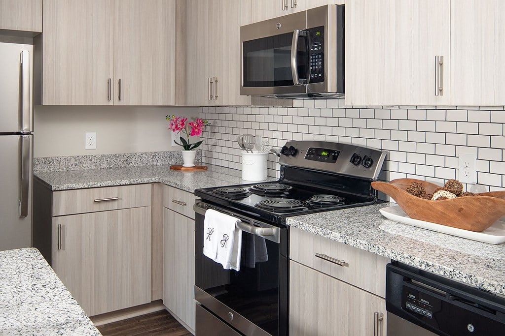 A kitchen with a black stove top oven and a microwave above it.
