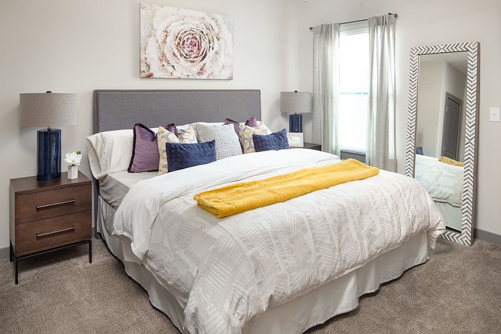 A bedroom with a large bed and a painting on the wall.