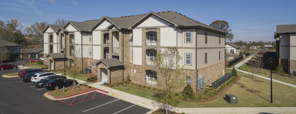 Apartment complex with a parking lot in front.