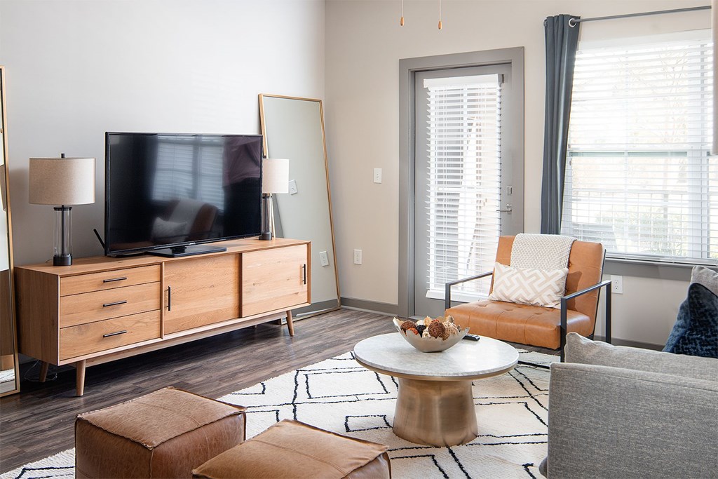 A living room with a television, a chair, a table, and a rug.