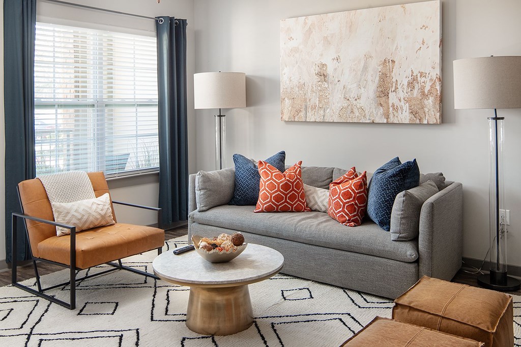 A living room with a grey couch, a chair, a coffee table, and a large painting on the wall.