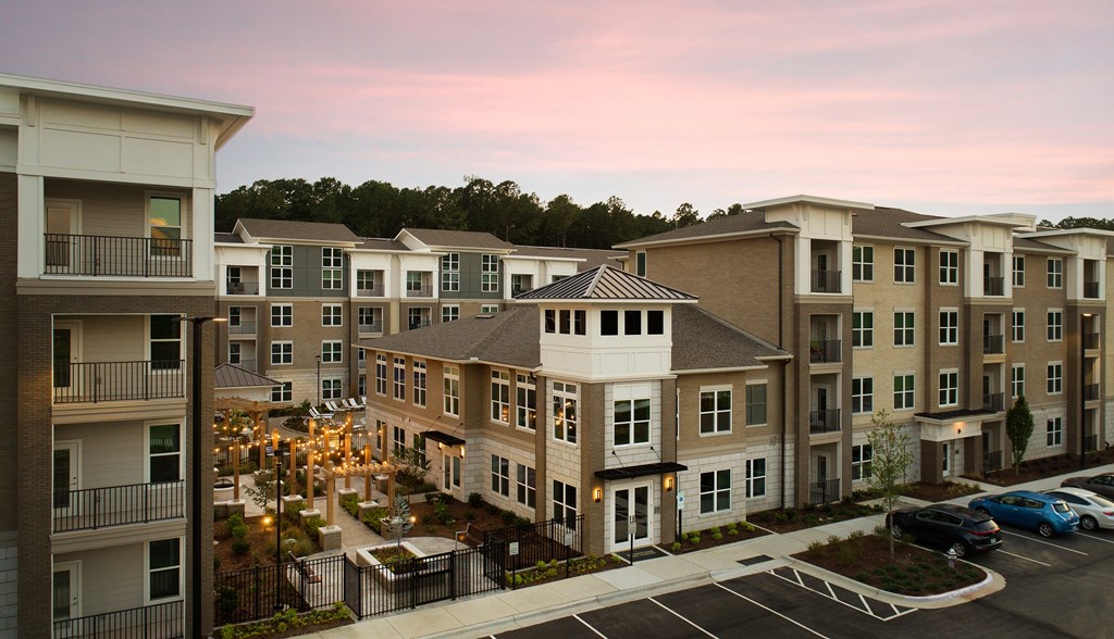 Apartment complex with a parking lot in front.