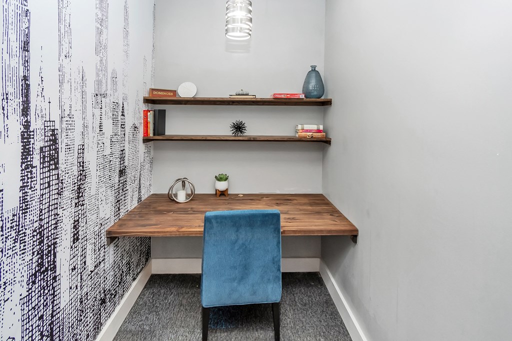 a small desk with a blue chair in a room with white walls and a black and white