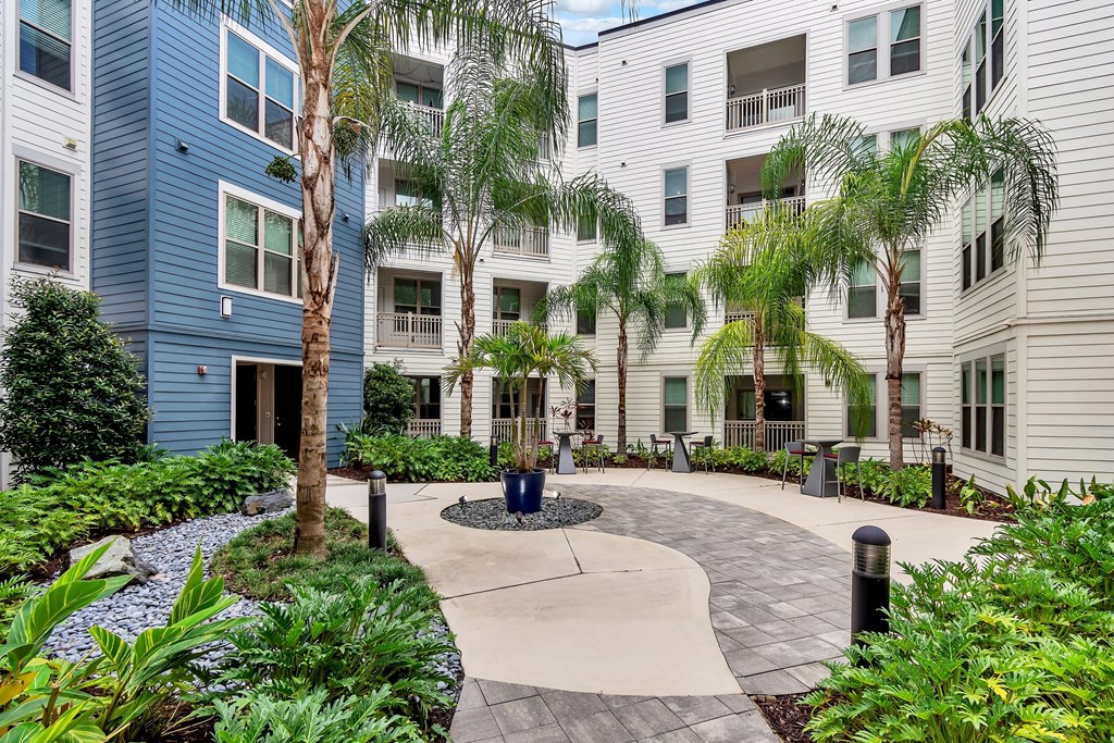 a circular walkway with trees and plants in front of an apartment building