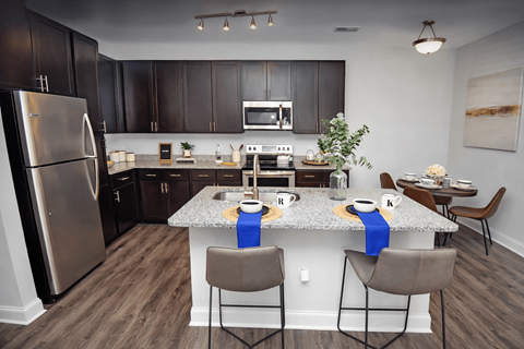 A kitchen with a table set for two with blue napkins.