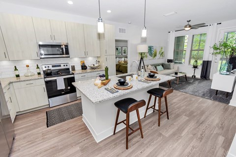 an open kitchen and living room with a marble counter top