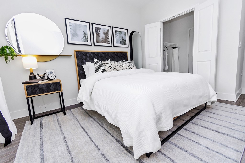 a bedroom with a white bedspread and black and white pictures on the wall
