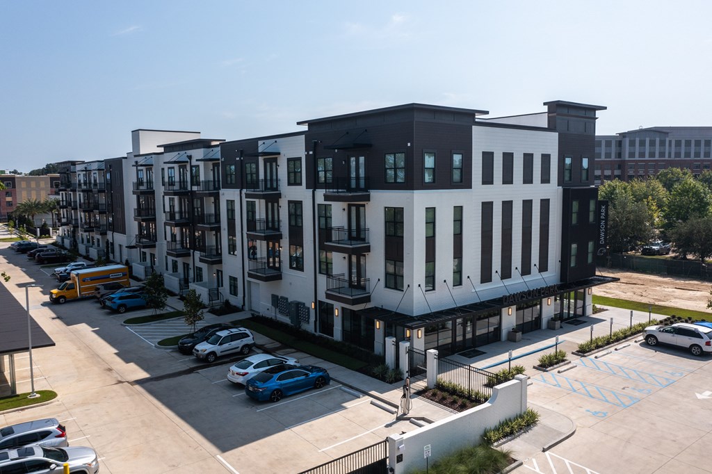 A modern apartment complex with a parking lot in front.