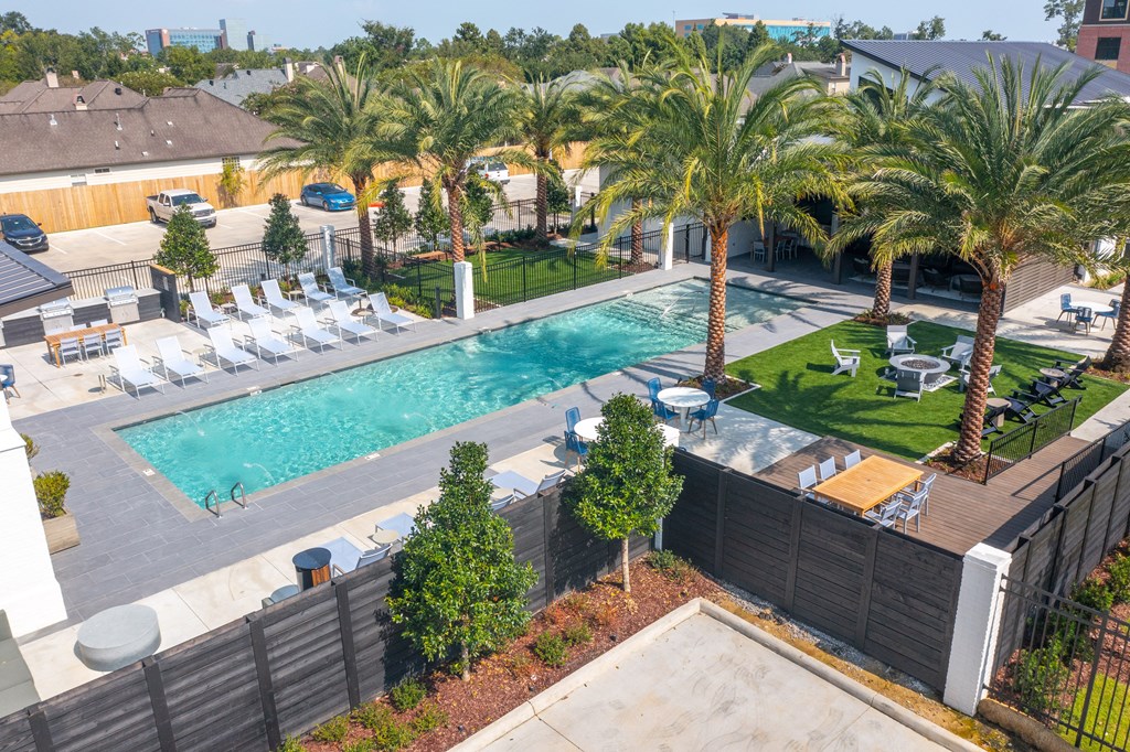 A pool surrounded by palm trees and lounge chairs.