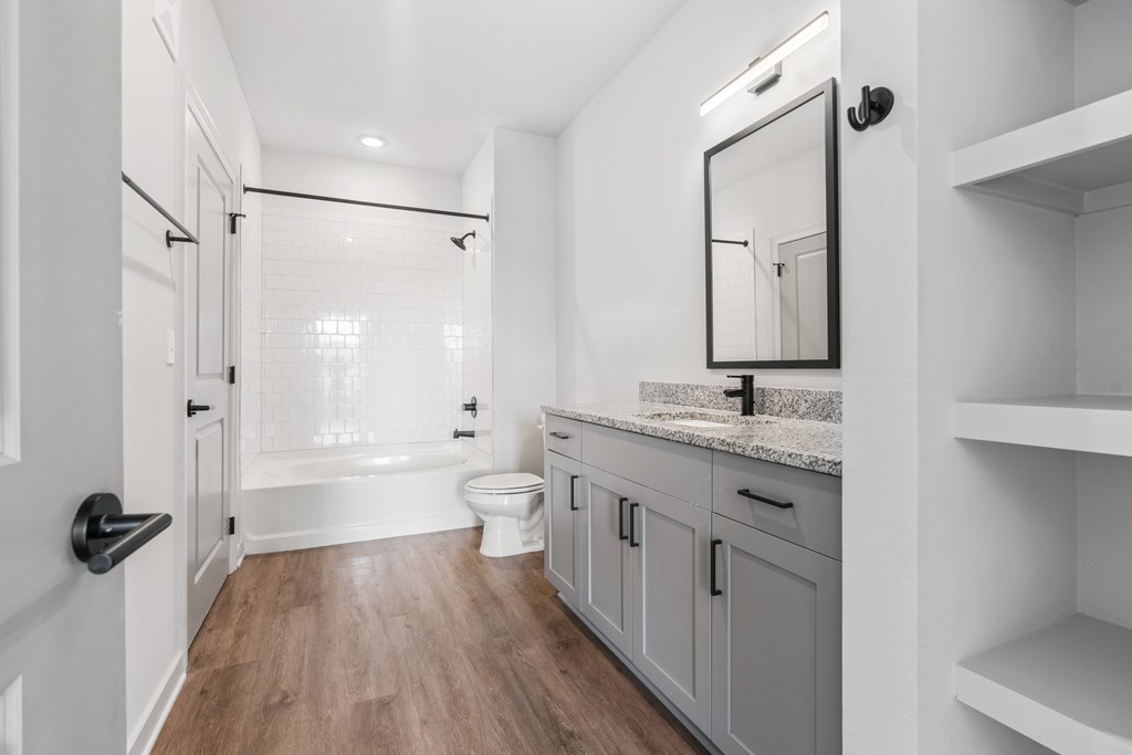 A white bathroom with a wooden floor and a walk-in shower.