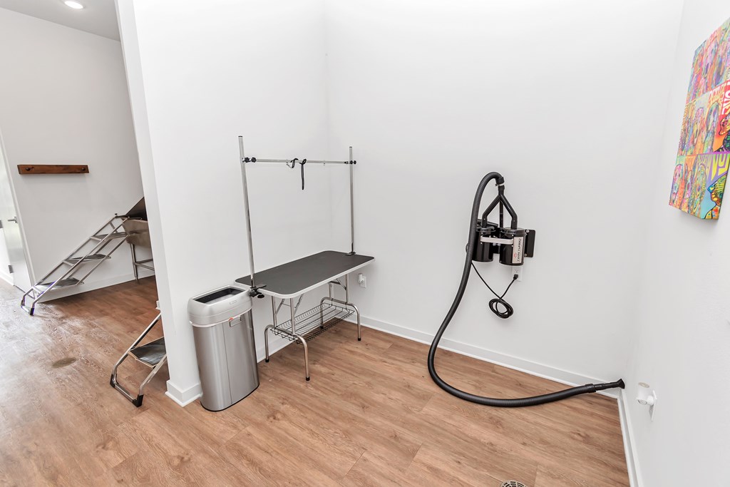 A room with a bench, a trash can, and a hose.