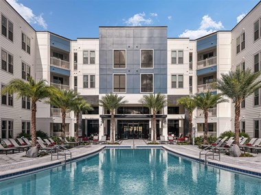 Well-maintained swimming pool and lounging chairs with parasols in Coda Orlando apartment rentals