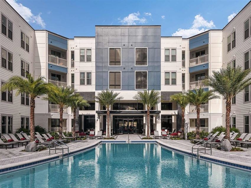 Well-maintained swimming pool and lounging chairs with parasols in Coda Orlando apartment rentals - Photo Gallery 1