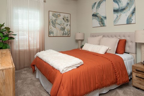a bedroom with an orange bed and a white blanket