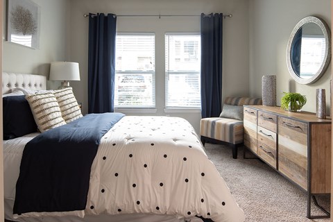 a bedroom with a bed and a dresser and two windows