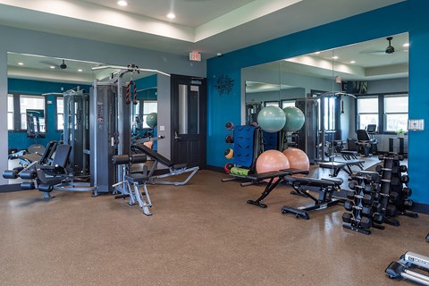 a fitness room with mirrors and exercise equipment in a gym
