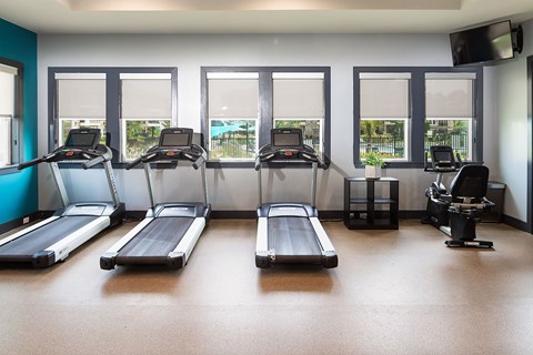 a gym with cardio equipment and windows in a building