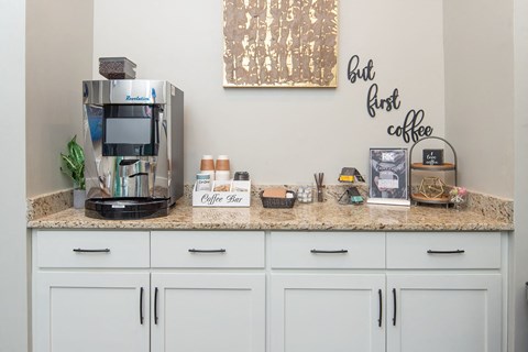 a kitchen with white cabinets and a counter top with a coffee maker