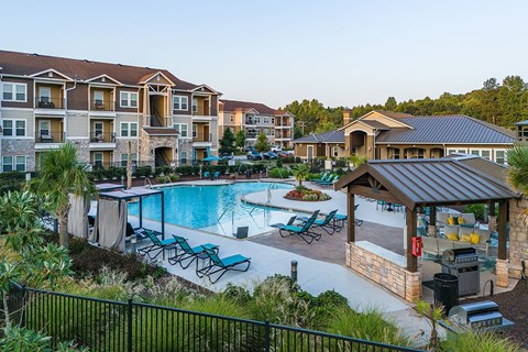 a large swimming pool with lounge chairs in front of an apartment building