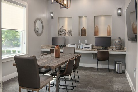 a business center with a table and chairs and a desk with computers