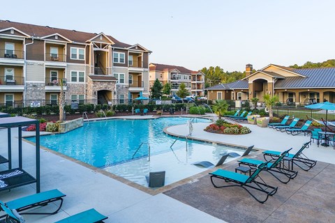 a swimming pool with lounge chairs and apartments in the background