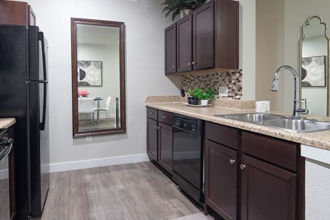 a kitchen with dark cabinets and a sink and a refrigerator