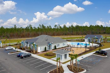 Aerial view of clubhouse, mailboxes, playground, swimming pool, and parking near tree-lined road - Photo Gallery 14