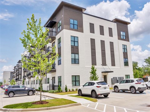 Modern four-story apartment building with balconies facing the front street parking