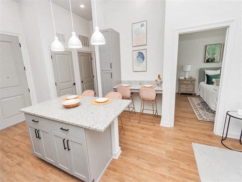 Kitchen island near a small dining nook with two chairs with access to the bedroom and entry way