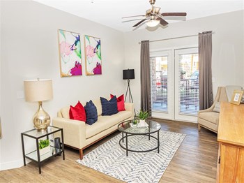 View of the living room with hard floors, a ceiling fan, and window french doors to the patio - Photo Gallery 4