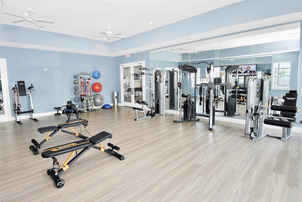 a large fitness room with cardio machines and weights