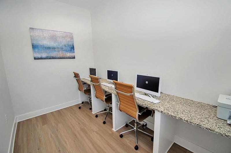 a desk with three computers on it and a painting on the wall