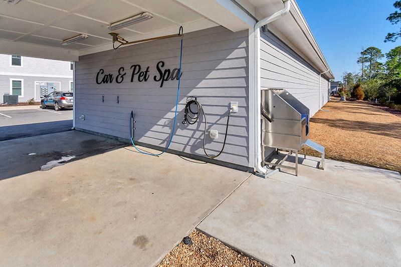 a carport with a grill and a hot tub in front of a house