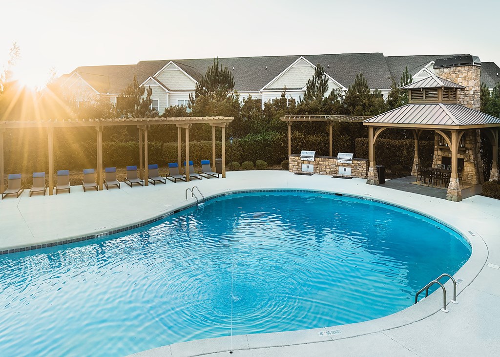 a swimming pool with chairs and a house in the background