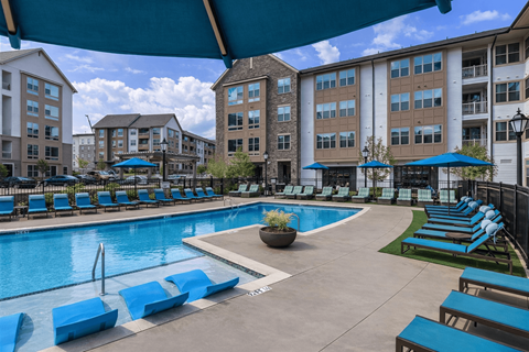 Swimming pool with blue loungers and umbrellas at Berewick Pointe Apartments, Charlotte, NC