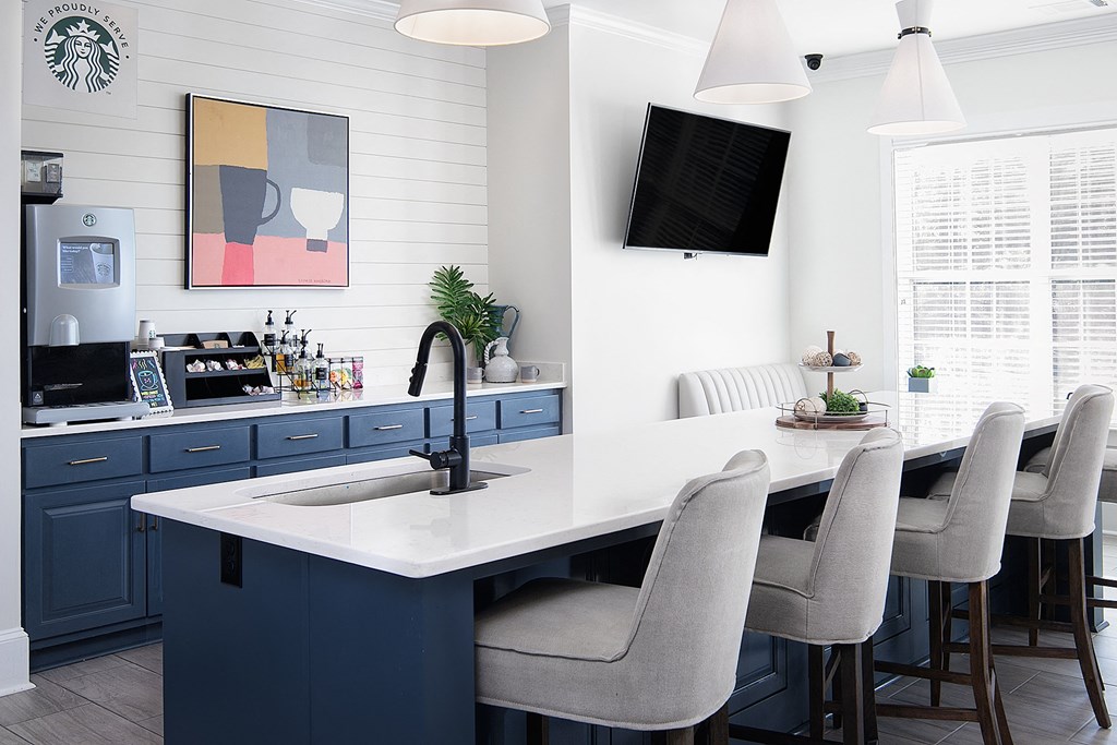 a kitchen with blue cabinets and an island with a sink and chairs