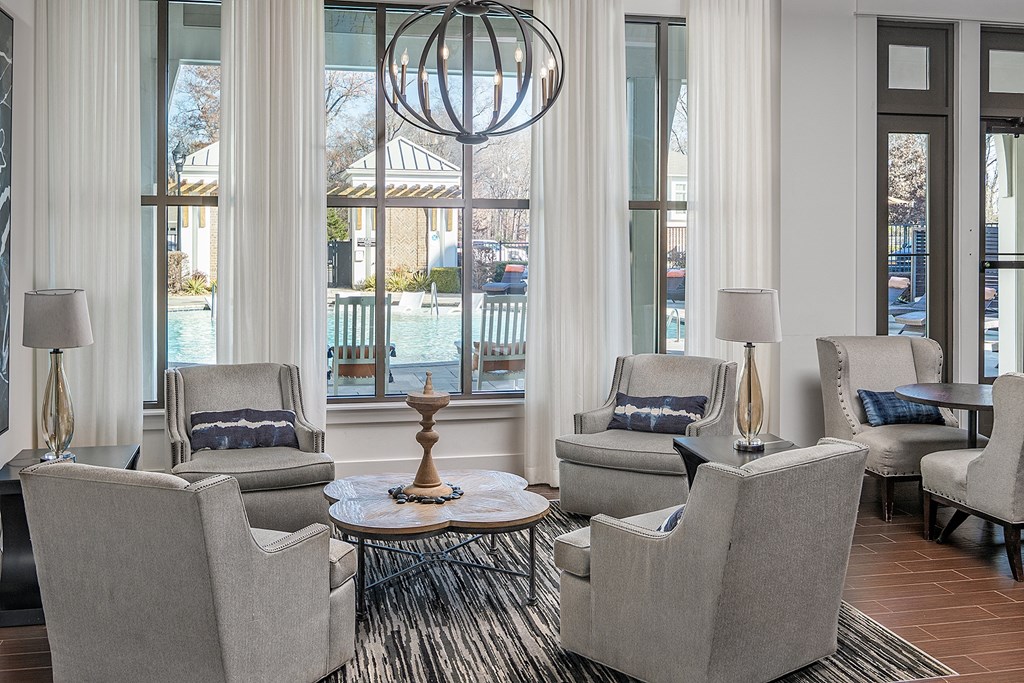 a clubhouse with chairs and a table and a view of a pool