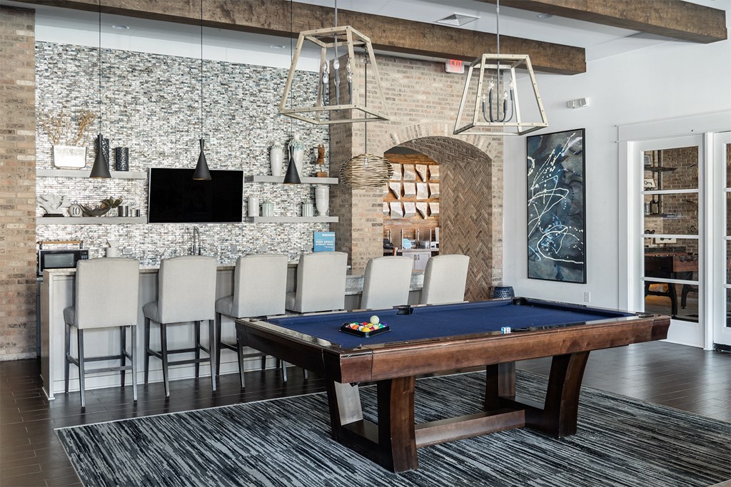 a pool table in a living room with a bar and a television