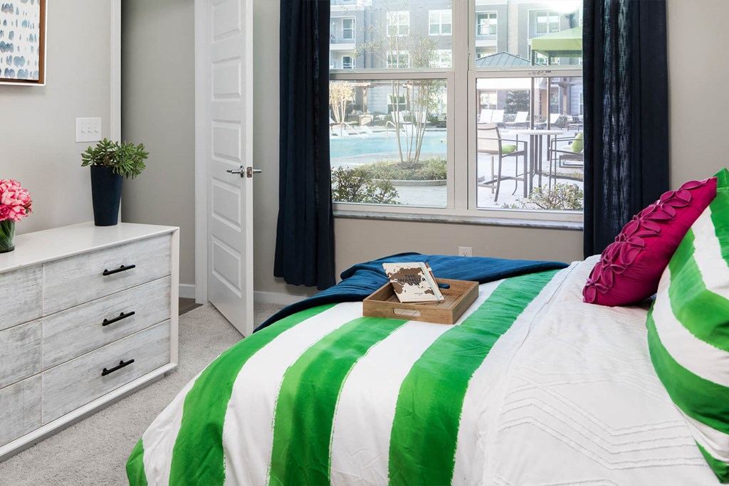 a bedroom with a bed with a green and white comforter and a window