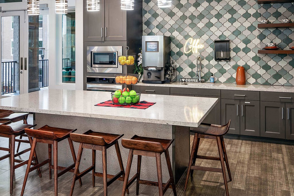 a kitchen in clubhouse with a large counter and some bar stools