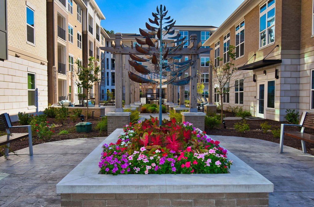 a planter with flowers and a metal tree in a courtyard
