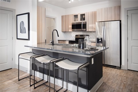 A kitchen with a black countertop and a fridge.