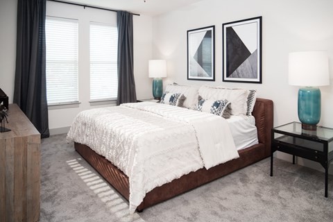 A bedroom with a large bed and two lamps.