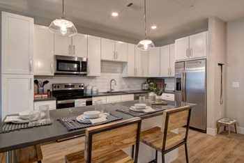 Furnished model kitchen has an island with barstools at Pointe at Research Park - Photo Gallery 4