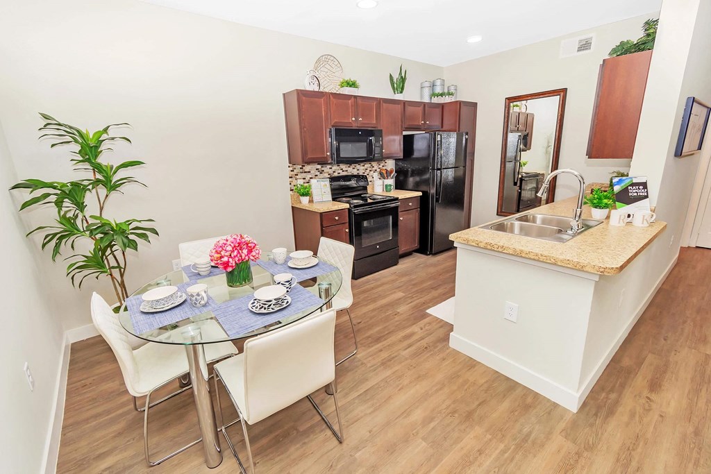 a dining area with a table and chairs and a kitchen in the background