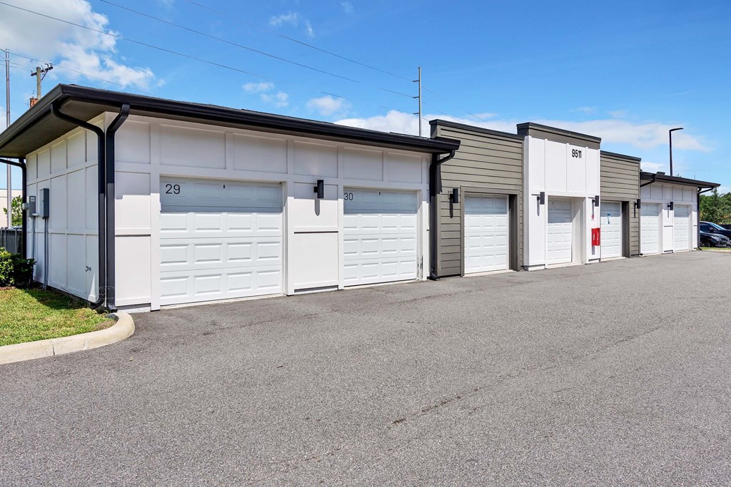 a row of garages with white doors and gray siding